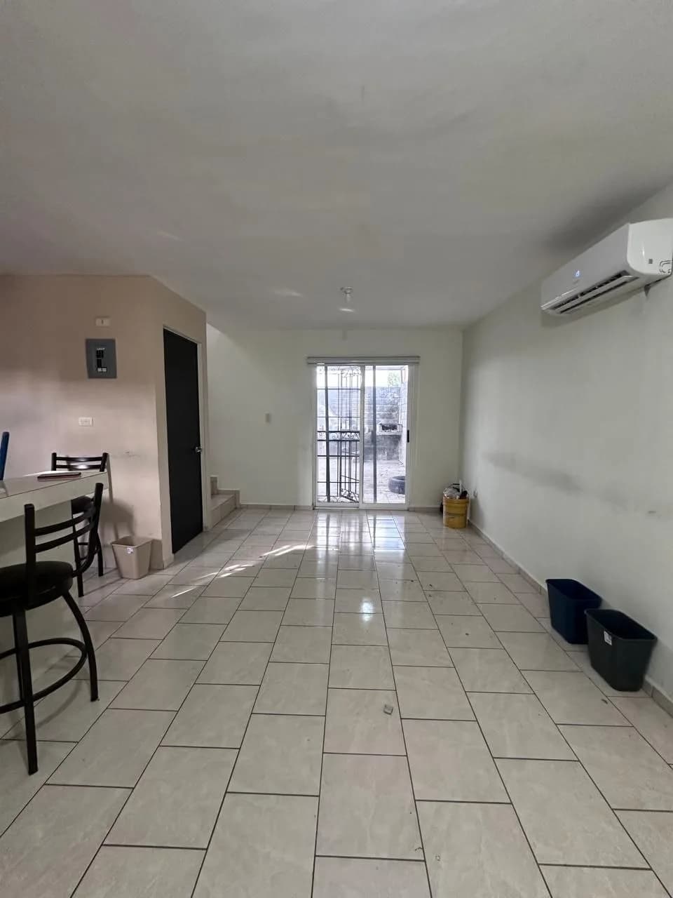 Sala interior con piso cerámico, aire acondicionado en la pared y puerta de cristal corrediza